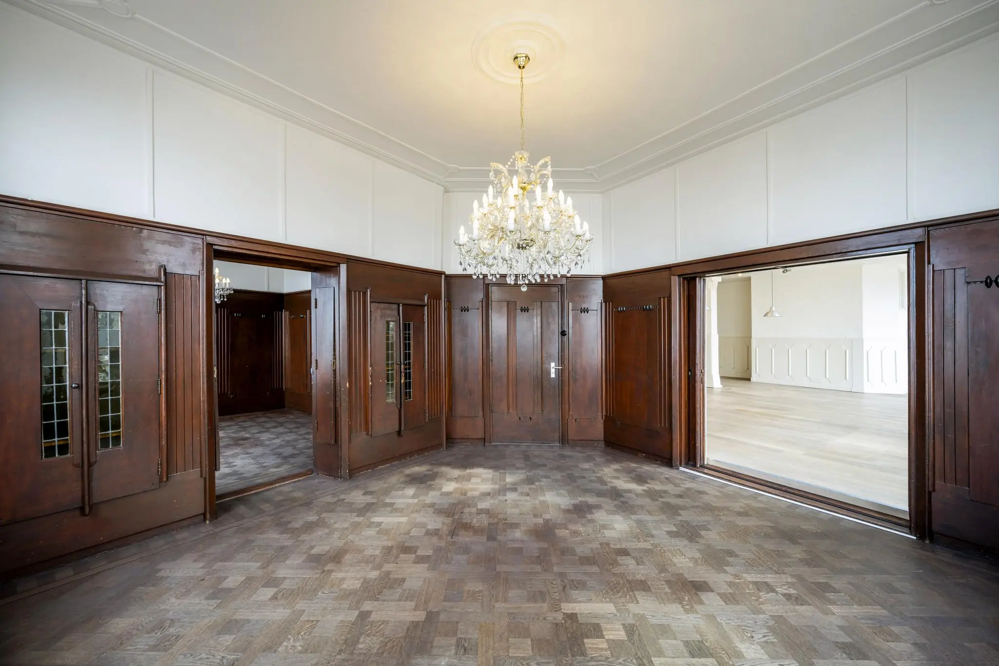 Elegante kamer aan de De Ruijterkade met houten lambrisering, visgraatparket en kristallen kroonluchter.